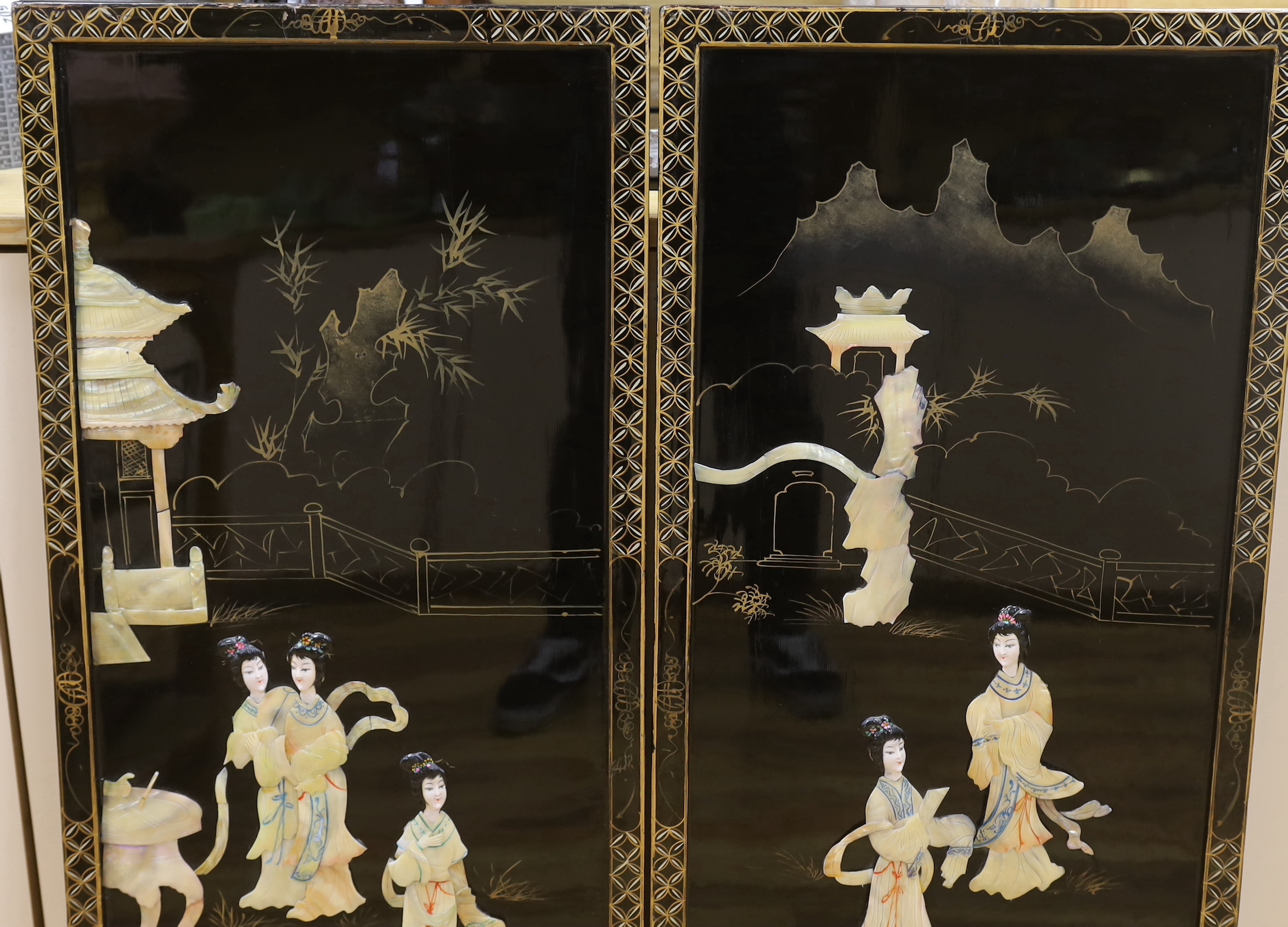 A pair of Chinese black lacquered panels, decorated in relief with females before pagodas, 92cm x 40cm